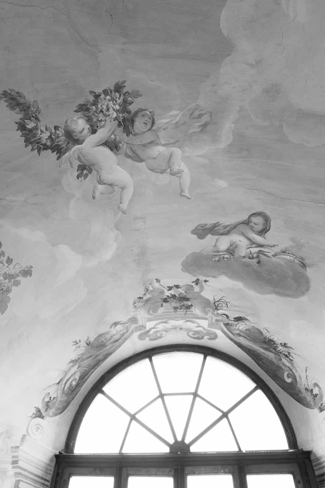 Barocke Deckenmalerei mit Engeln und Blumen über einem Bogenfenster