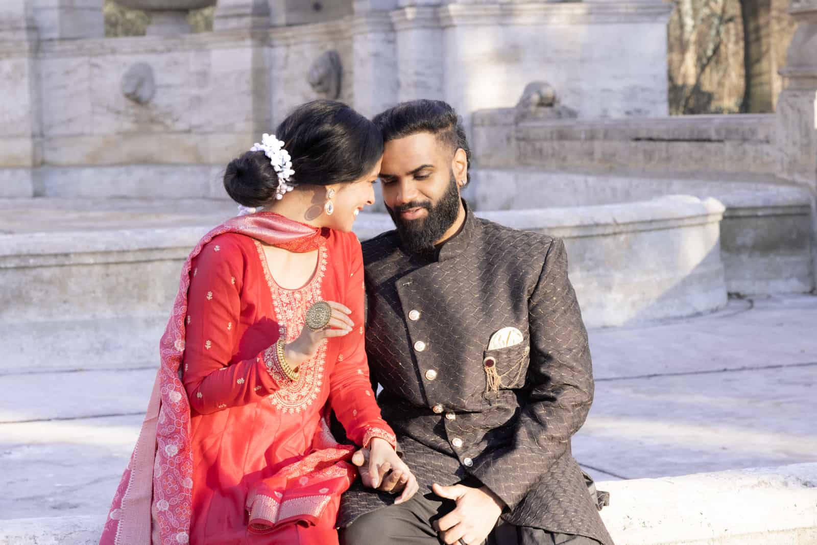 Indisches Brautpaar sitzt in traditioneller Hochzeitskleidung vor historischer Kulisse in Berlin