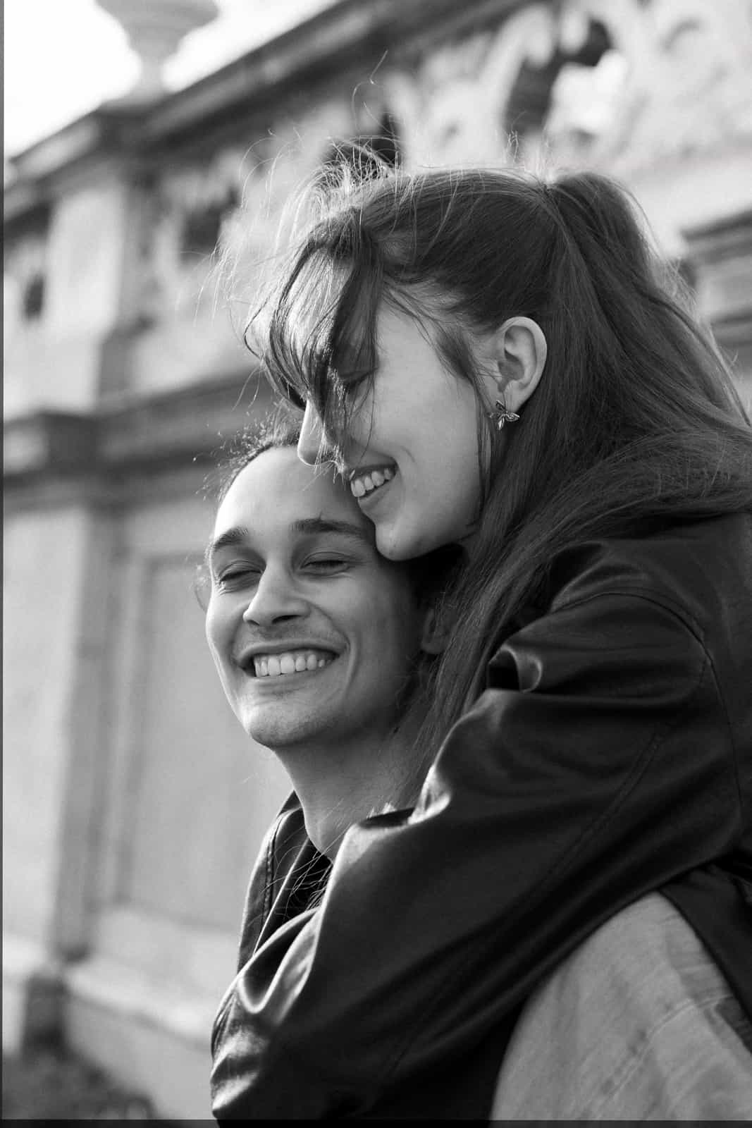 Lachendes Paar Huckepack vor historischem Gebäude in Schwarz-Weiß