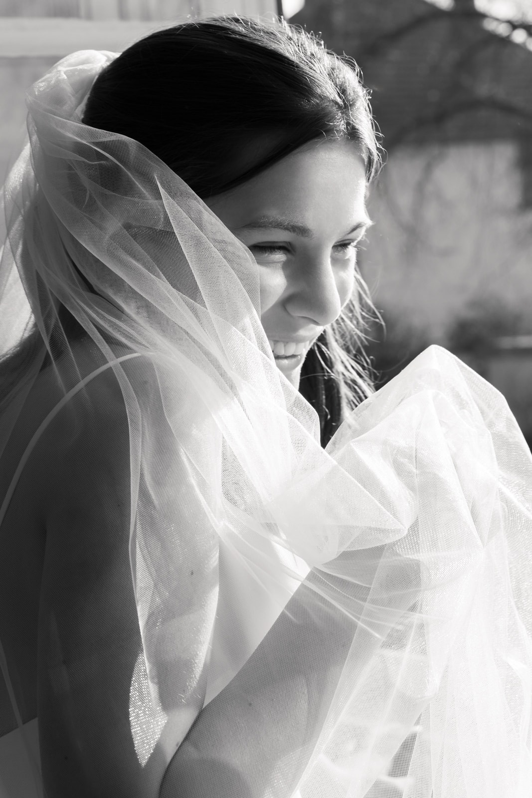 Bride smiling gently wrapped in delicate wedding veil