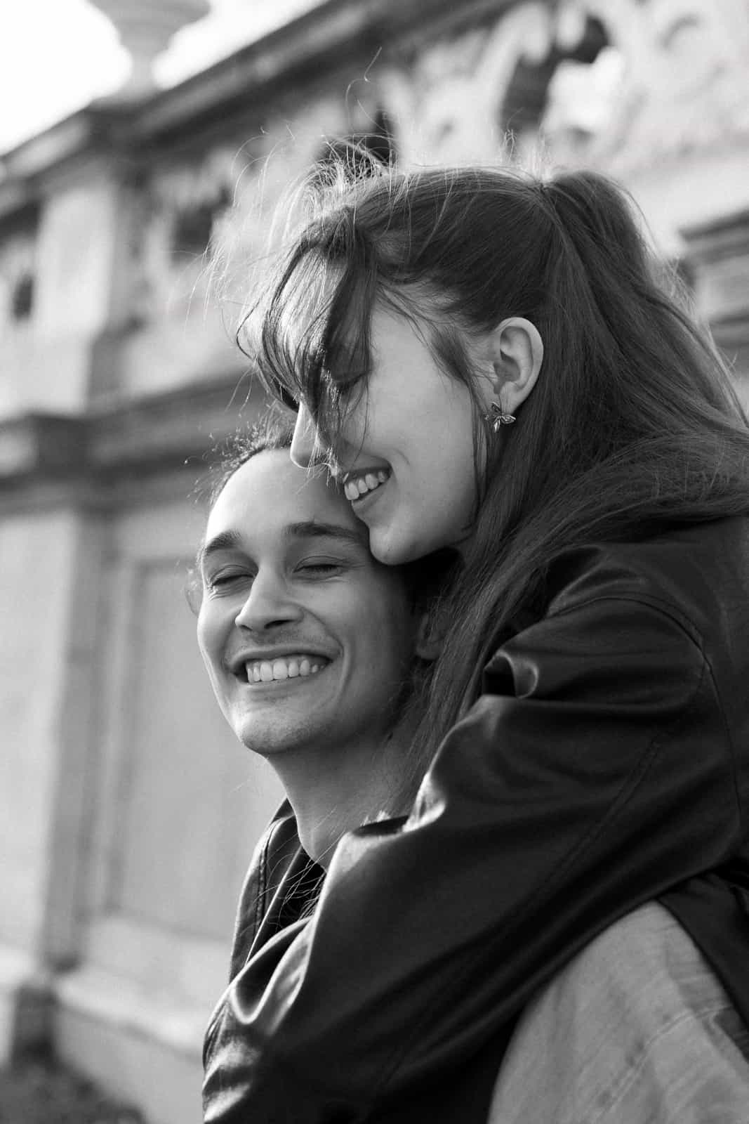Laughing couple piggyback in front of historic building in black and white