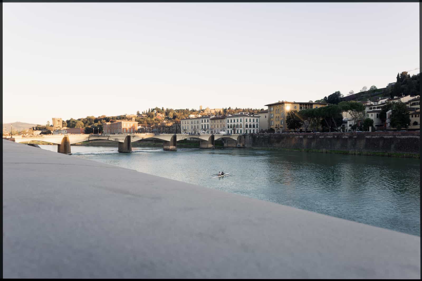 Arno river in Florence with bridge and rower at golden hour