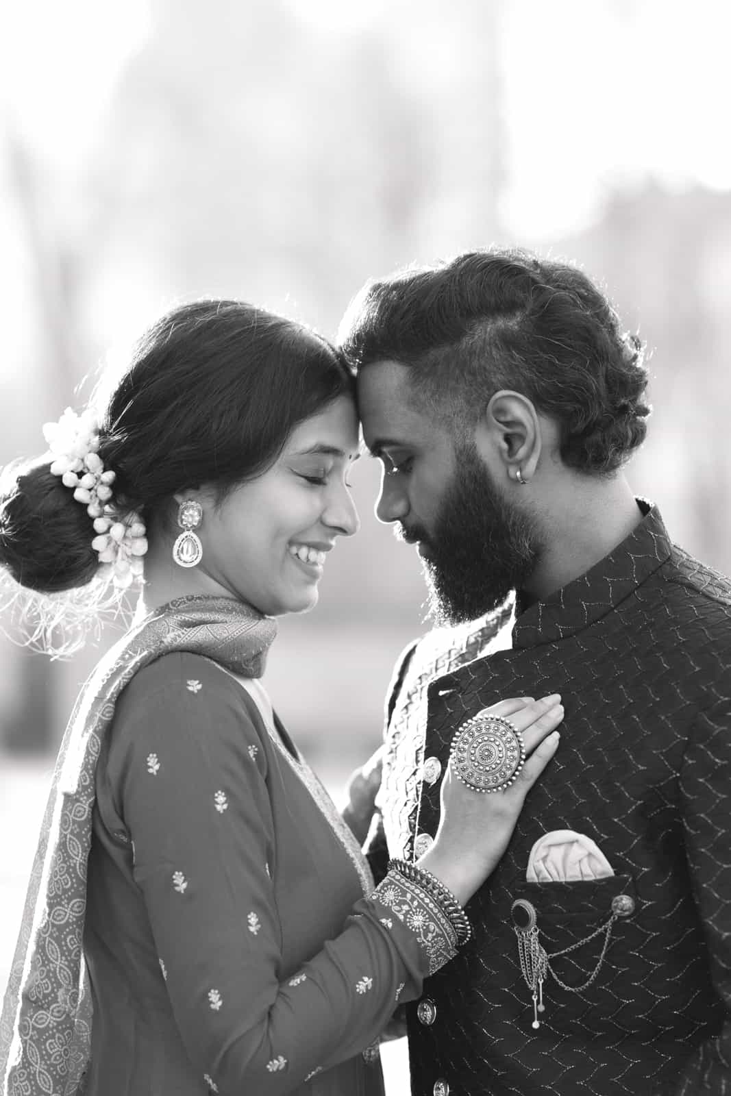 Indian wedding couple in traditional attire with floral accessories and jewelry smiling at each other during wedding in Berlin Brandenburg