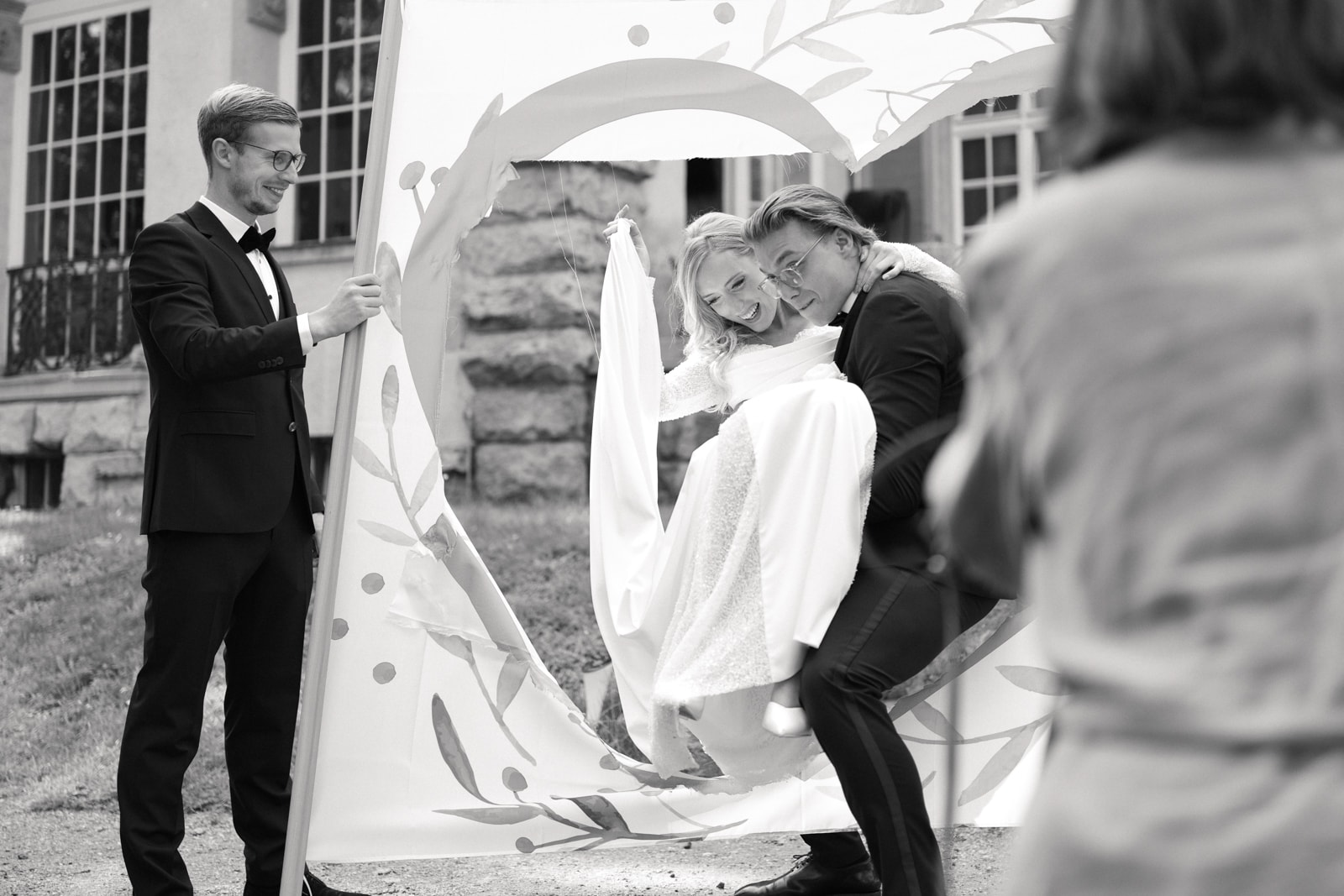 Bride and groom laughing together at outdoor ceremony with decorative backdrop