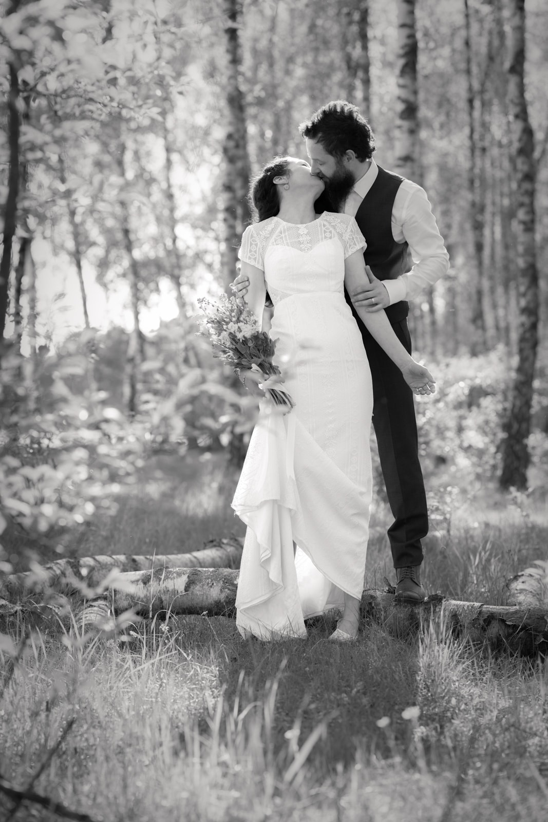 Wedding couple kissing in sun-drenched forest