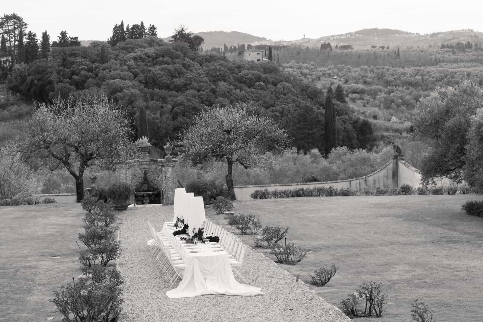 Long white wedding table between olive trees in Tuscan landscape