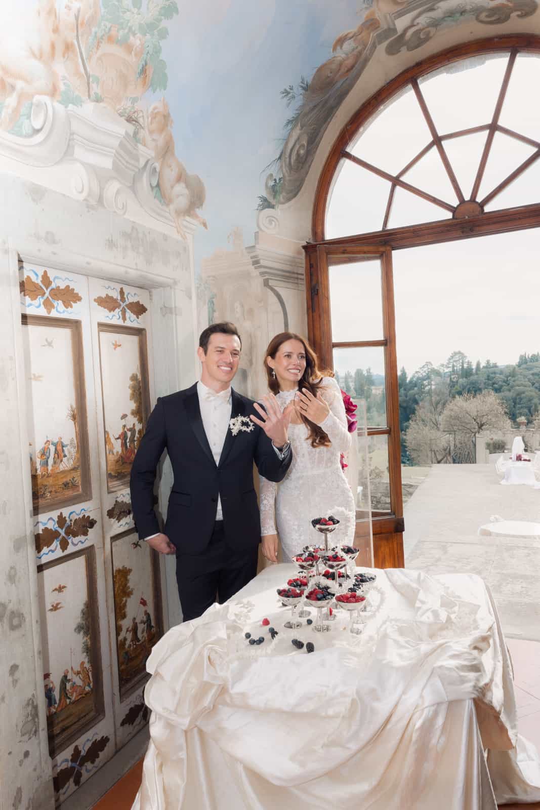 Wedding couple laughing at the cake table in a baroque frescoed hall
