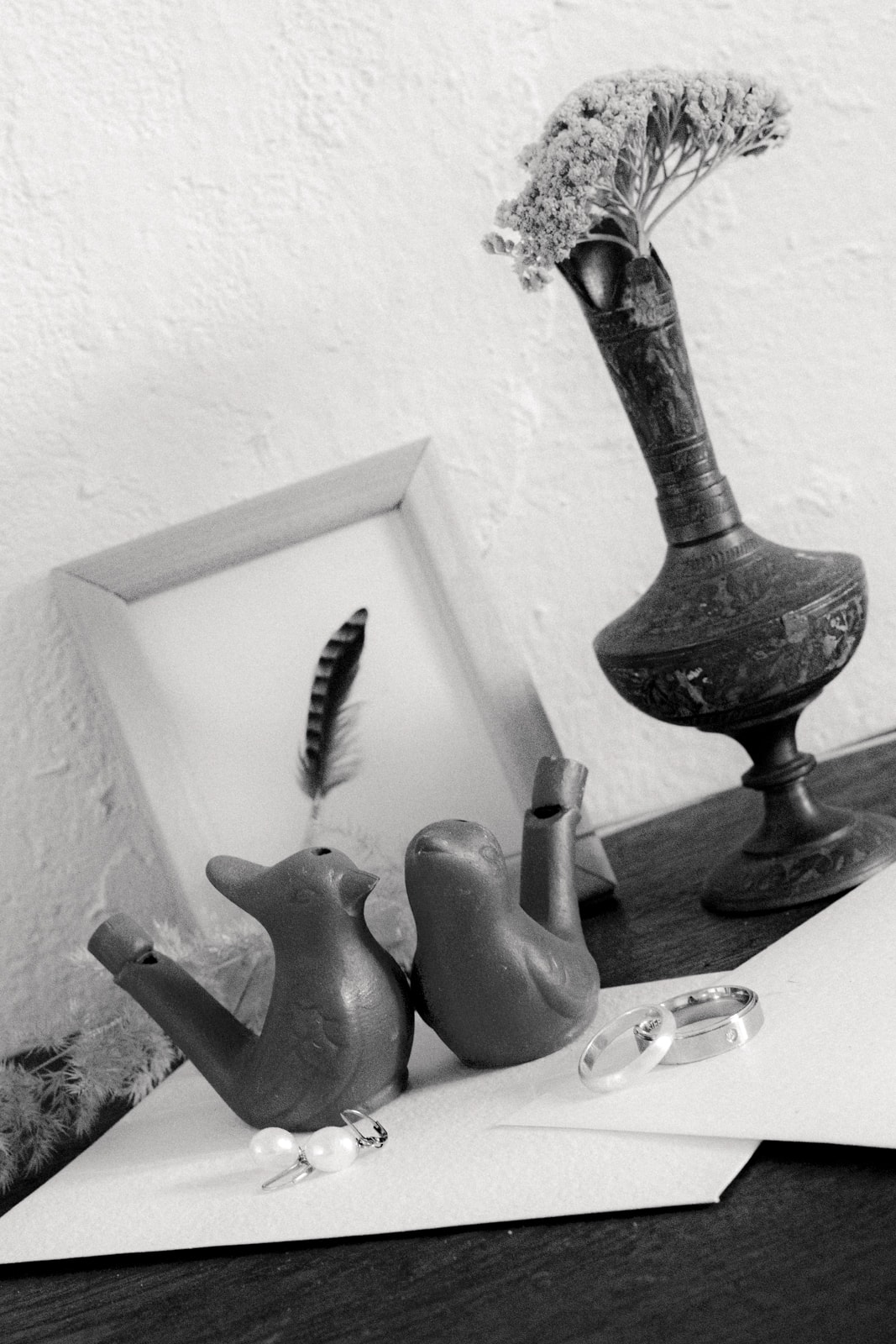 Black and white still life with wedding rings, vases, birds and jewelry
