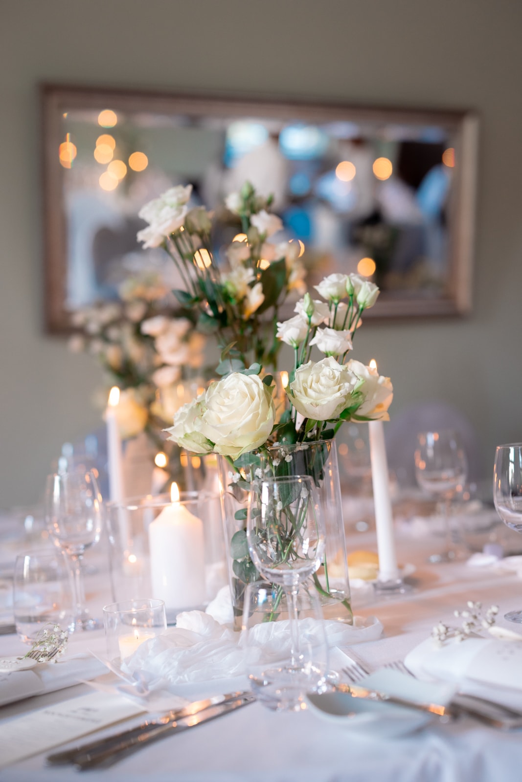 Wedding reception table with white roses and candles in elegant setting